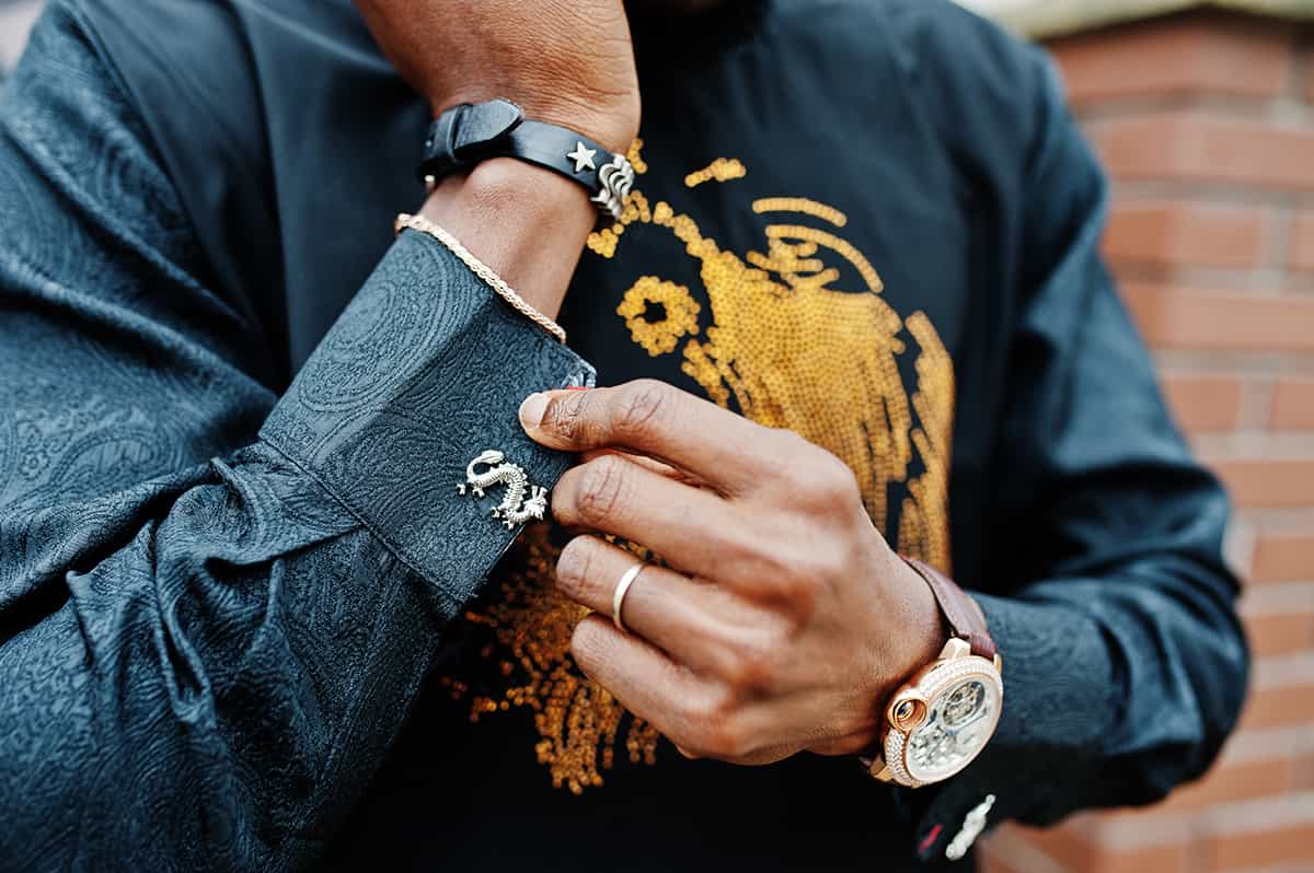 close up hands rich african man with watch cufflinks