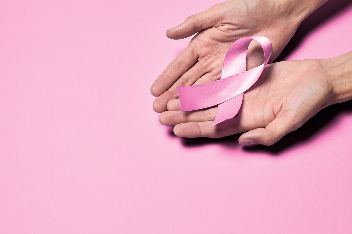 hands hold pink ribbon breast cancer concept
