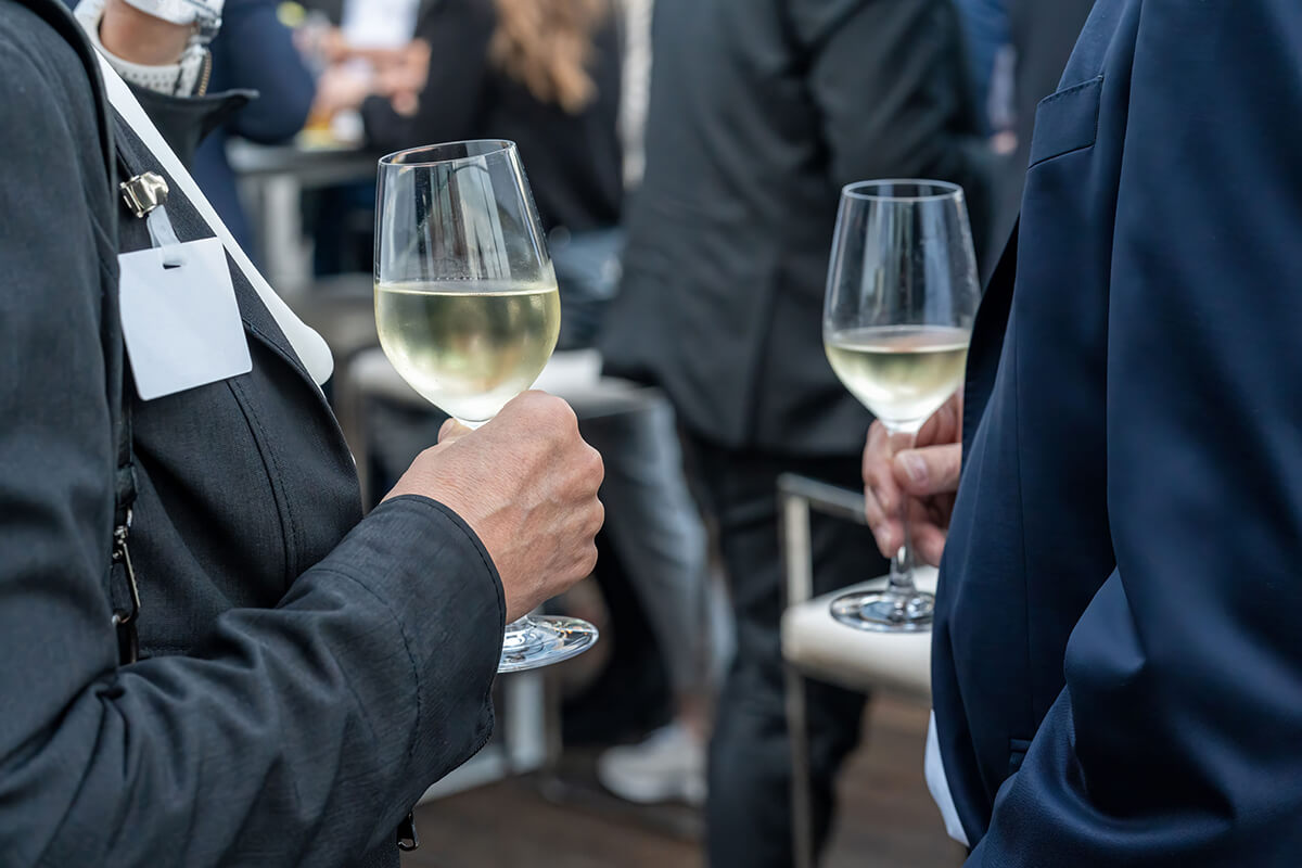 suited businessmen holding each a glass of wine