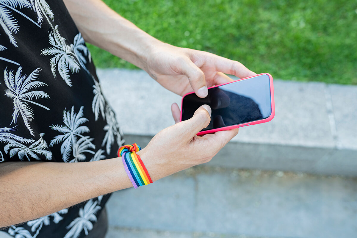 man's hands chatting with a mobile wearing lgbt